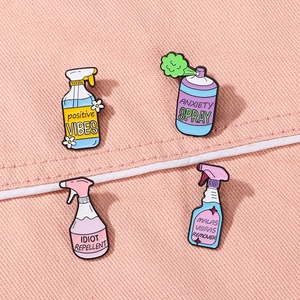 Detail view of four colorful enamel pins featuring humorous spray bottle cartoon designs