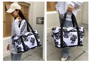 Detail view of large white travel bag with elephant print and black adjustable straps