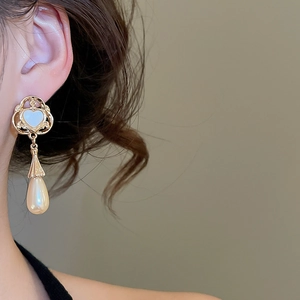 Close-up of heart pearl drop earrings featuring vintage style on model's ear