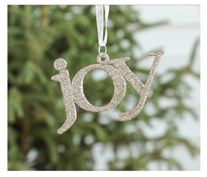 Macro detail of golden glitter 'joy' letter ornament hanging on a Christmas tree