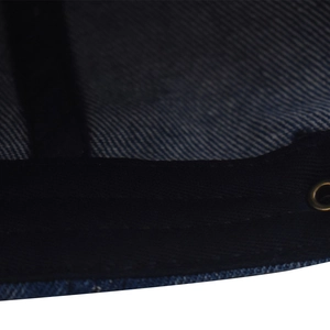 Macro detail of navy washed denim fabric with sweatband and a gold metal eyelet on baseball cap