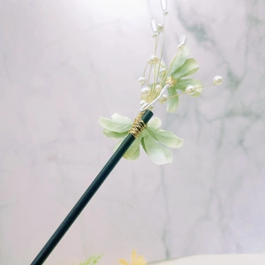 Détail de fleurs en velours vert et perles blanches sur un pic à cheveux chinois
