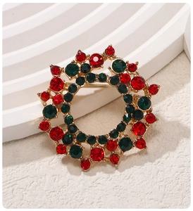 Close-up of a Christmas wreath brooch with red and green rhinestones on gold metal base