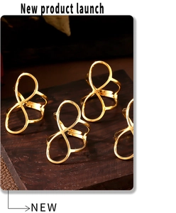 Macro detail of four gold figure-eight open rings with 18K PVD finish on wood background