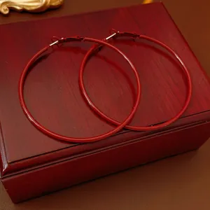 Glossy red circular hoop earrings with silver pins displayed on a vintage jewelry box