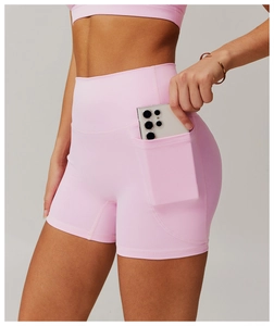 Macro shot of high-waist pink yoga shorts with functional side pocket holding a phone
