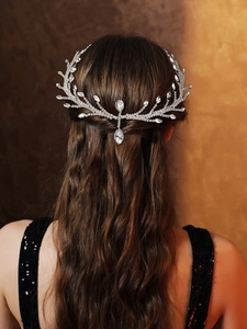 Macro shot of silver crystal hair chain with leaf branch design on female bridal hairstyle