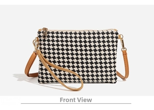 Detail of checkered woven straw bag with brown leather straps and gold metal hardware