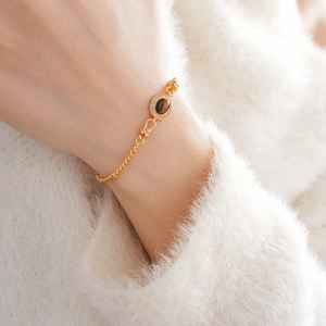 Close-up of gold-plated tiger eye bracelet with micro-pave cubic zirconia on female wrist