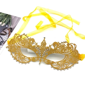 Golden lace masquerade mask with sparkling rhinestones and yellow silk ribbons on white backdrop