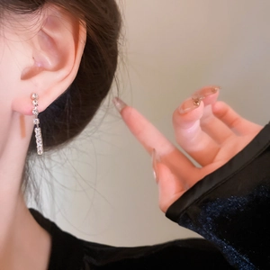 Close-up of silver tassel earrings with sparkling crystals worn by a model