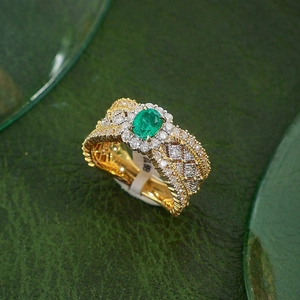 Macro shot of an emerald gemstone ring with diamond halo and woven gold lattice detail