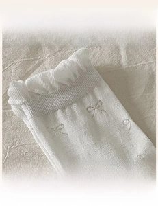 Detail of high-elasticity ribbed cuff and delicate bow pattern on white cotton socks
