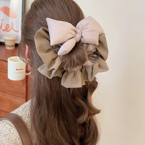 Close-up of a large puffy bow scrunchie with beige mesh and brown plaid fabric details