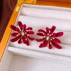 Detailed close-up of velvet red flower earrings with zircon centers in a jewelry box