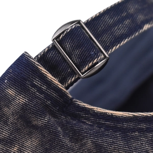 Detail of the adjustable black metal buckle on a distressed blue denim baseball cap