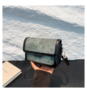 Detailed shot of grey denim and black leather crossbody bag with silver metal clasp