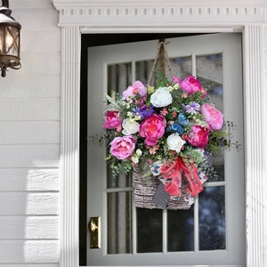 Close-up of artificial floral door basket with pink peonies, daisies and a red bow