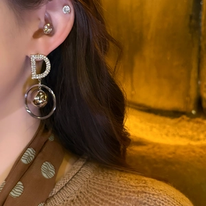 Letter D drop earrings with sparkling rhinestones and golden bead detail on female model