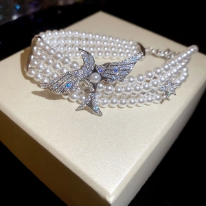 Vue détaillée d'un bracelet de perles multicouches avec breloque oiseau en zircons