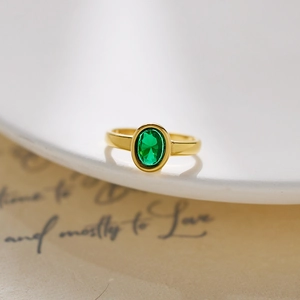 Detail of vintage gold stainless steel ring with oval green stone on white ceramic