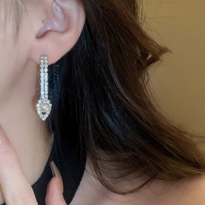 Gros plan de boucles d'oreilles pendantes argentées avec perles et strass sur modèle