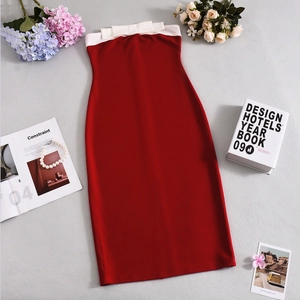 Detail of red tube dress featuring a white contrast bow and slim fit knitted fabric