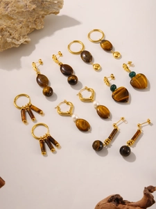 Detailed close-up of tiger eye stone and pearl earrings with Lucky engraving