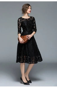 Detail of elegant black lace dress featuring intricate floral hollow textures and A-line hem