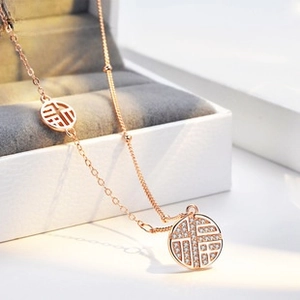 Macro detail of rose gold Fu pendant necklace with pavé diamonds on jewelry box