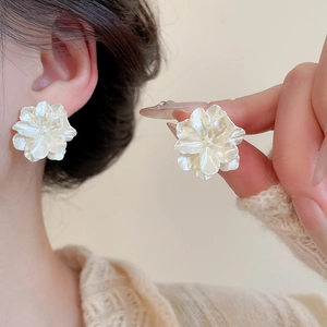 Macro di orecchini a fiore 3D con petali bianchi perlescenti indossati sull'orecchio