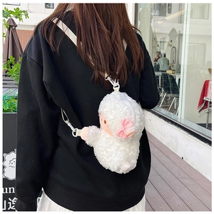 Cute white plush lamb crossbody bag with pink bow accessory shown on a model outdoors