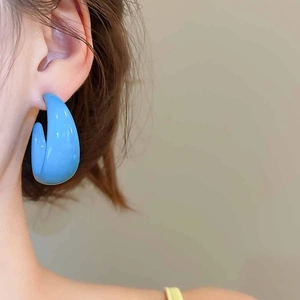 Close-up of bright blue acrylic C-shape hoop earring on a model with a glossy finish