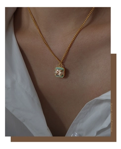 Detail of a vintage gold necklace featuring a turquoise enamel square pendant and zircon
