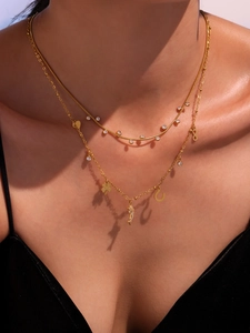 Detail of layered gold necklaces with zircon crystal pendants on model skin