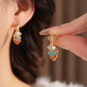 Close-up of gold-plated vintage earrings with colorful zircons and flower tassel design