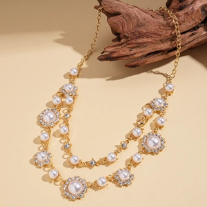 Close-up van dubbellaagse gouden ketting met parels en zirkoon bloembedeltjes op hout