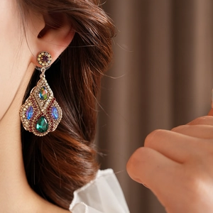 Gros plan de boucles d'oreilles vintage en or avec pierres colorées portées par un mannequin