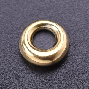 Macro shot of polished gold-finished circular ring pendant with smooth metallic texture