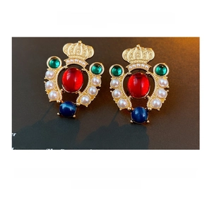 Detail of vintage crown stud earrings featuring red and blue gems on a book backdrop