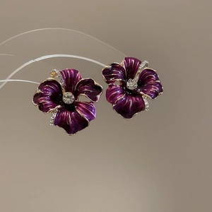 Vue macro de boucles d'oreilles fleurs en émail violet avec cristal et bord doré