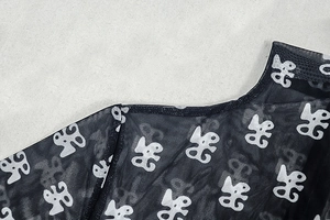 Detail of sheer mesh fabric with white logo pattern on black long sleeve bodysuit
