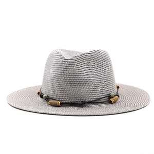 Détail d'un chapeau de paille gris avec perles bohèmes et cordon décoratif marron