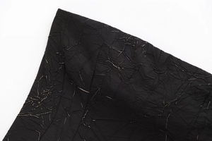 Close-up of black pleated texture with metallic silver crackle details on the fabric