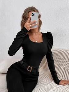Detail of black square neck knit top with puff sleeves worn with a buckled belt