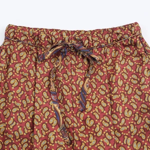 Detail of red paisley print fabric featuring a drawstring elastic waistband on the trousers