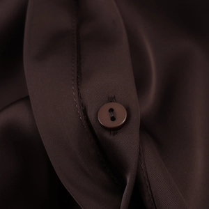 Detailed macro view of smooth dark brown satin fabric with a matching round button