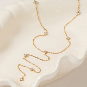 Collier élégant en acier inoxydable doré avec zircons clairs sur un plateau en céramique