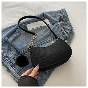 Détail du sac bandoulière noir en feutre matelassé avec chaîne dorée et pompon doux