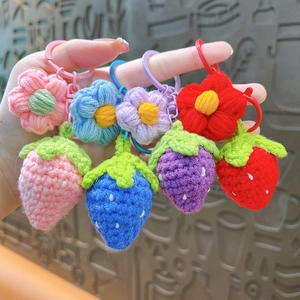 Handmade crochet strawberry and flower keychains in pink, blue, purple, and red colors